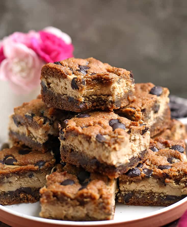 stack on grain free chocolate chip cookie cheesecake bars on a plate, the middle layer showing 