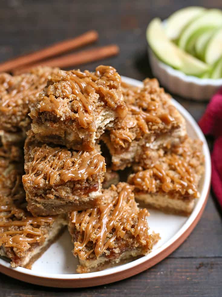 stack of grain free caramel cheesecake bars on a plate with a bite taken out of the top one 