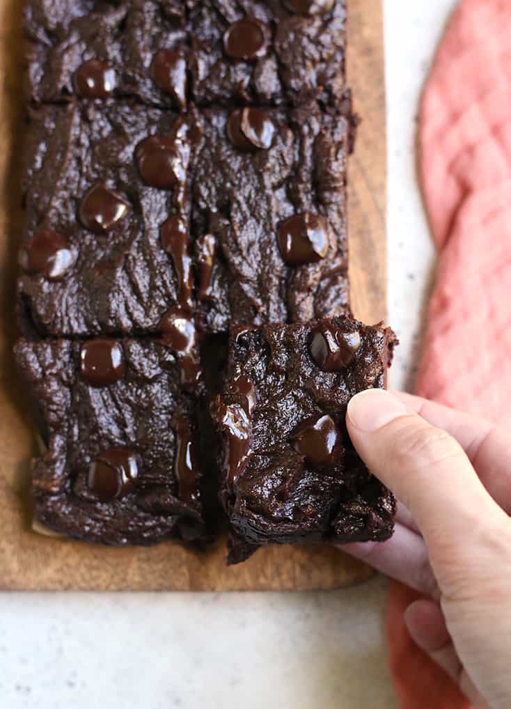 hand grabbing a paleo vegan brownie with chocolate chips on top 