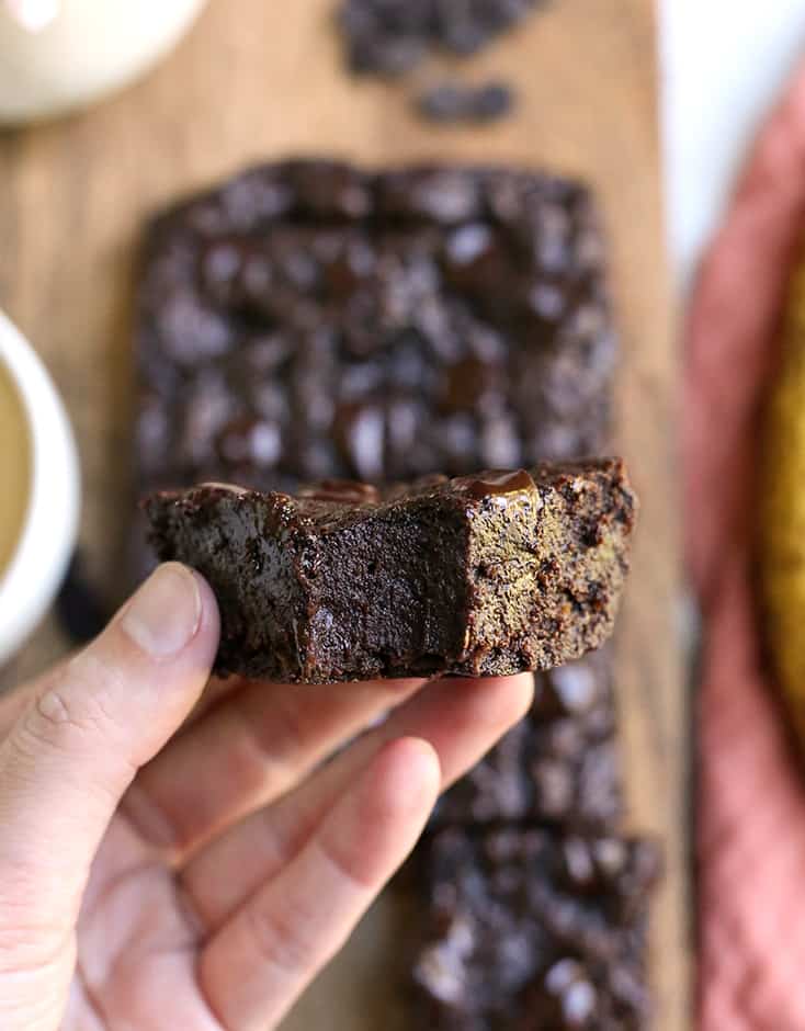 hand holding a vegan nut free brownie with a bite taken out of it 