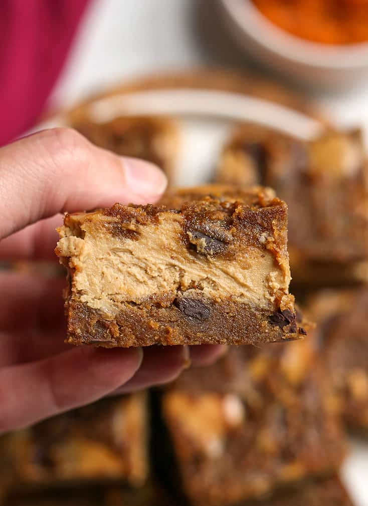 hand holding a grain free pumpkin cheesecake bar, the layers showing 