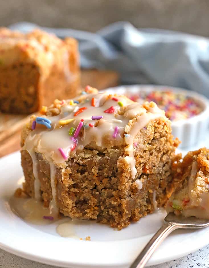 a piece of paleo coffee cake with a bite taken out and glaze dripping down 