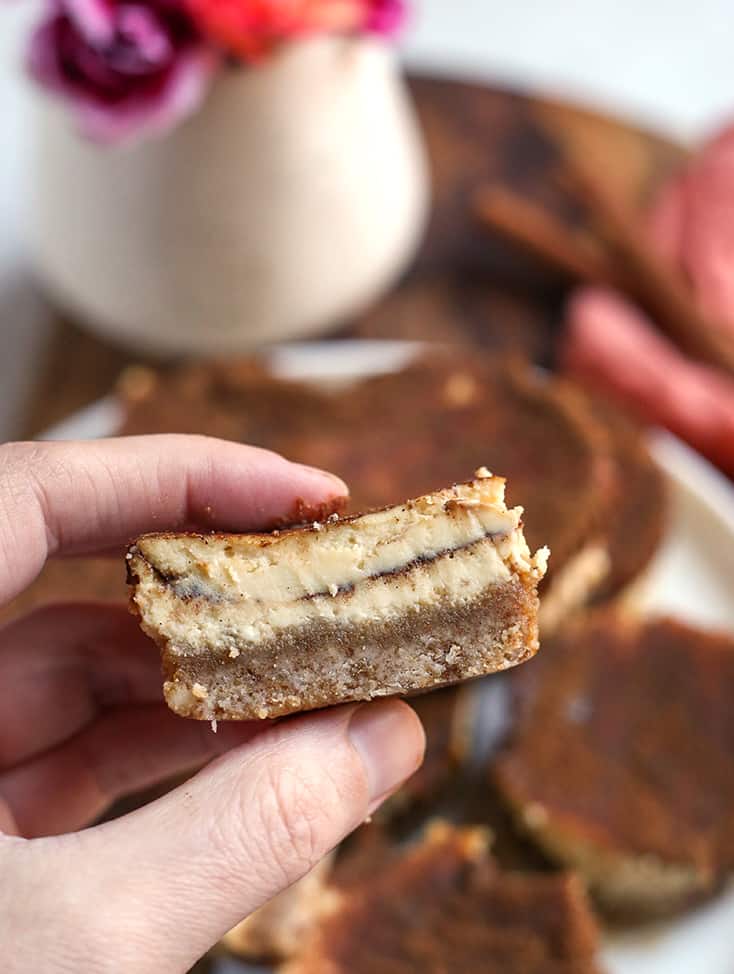 hand holding a cinnamon roll cheesecake, showing the middle 