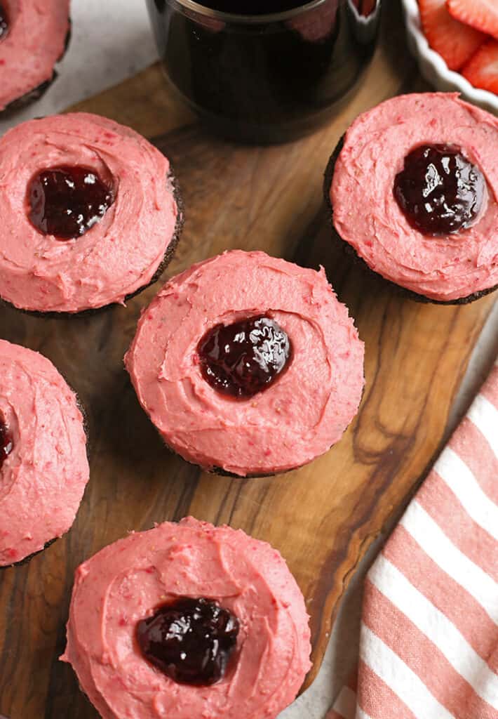 top view of gluten free chocolate cupcakes with strawberry frosting on a wooden board 