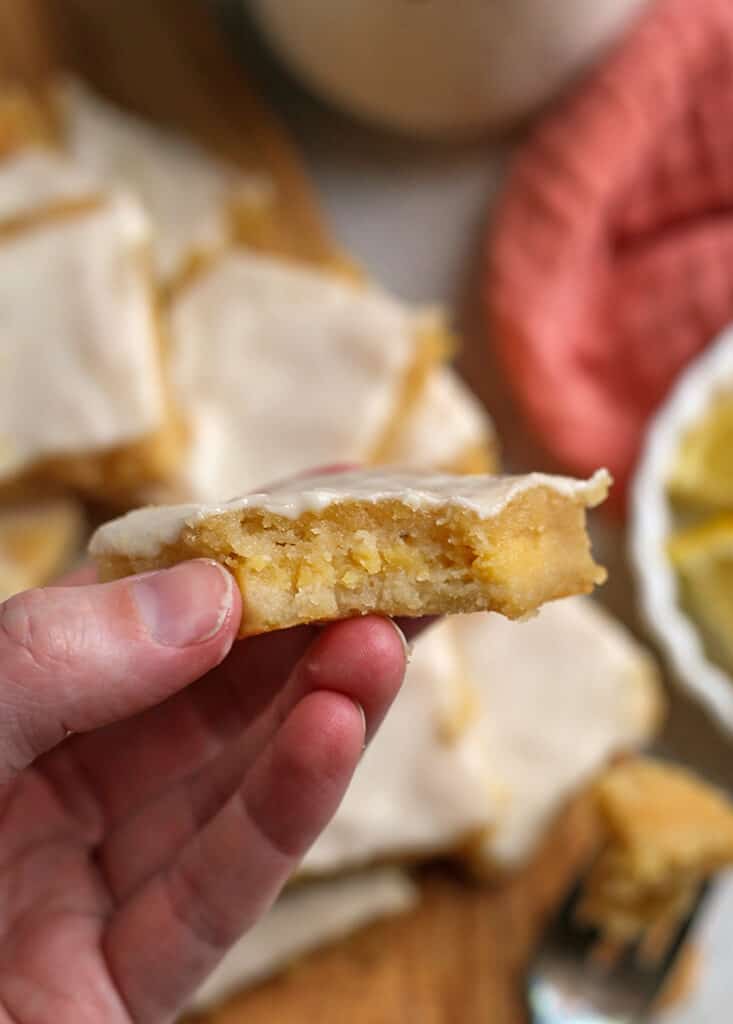 hand holding a grain free lemon bar with a bite taken out 