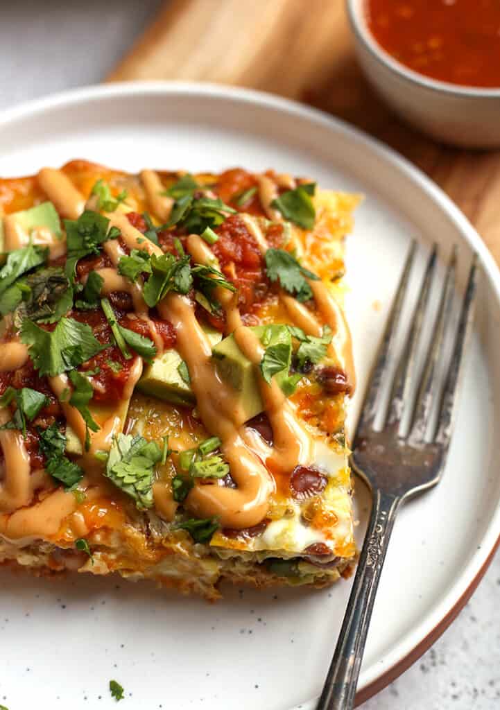 close view of a piece of Mexican egg bake on a plate, loaded with toppings 