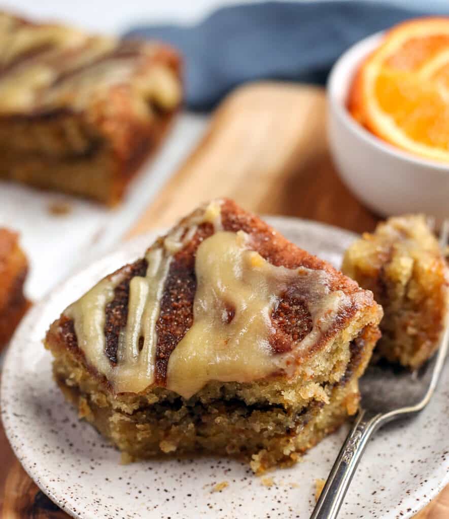 close image of paleo orange cinnamon coffee cake with a bite taken out, showing the glaze on top. 